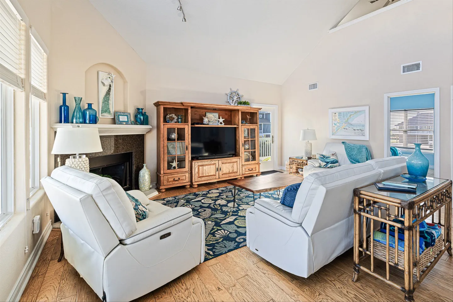 Living room with vaulted ceilings, a fireplace, wood entertainment center, and white reclining armchairs.