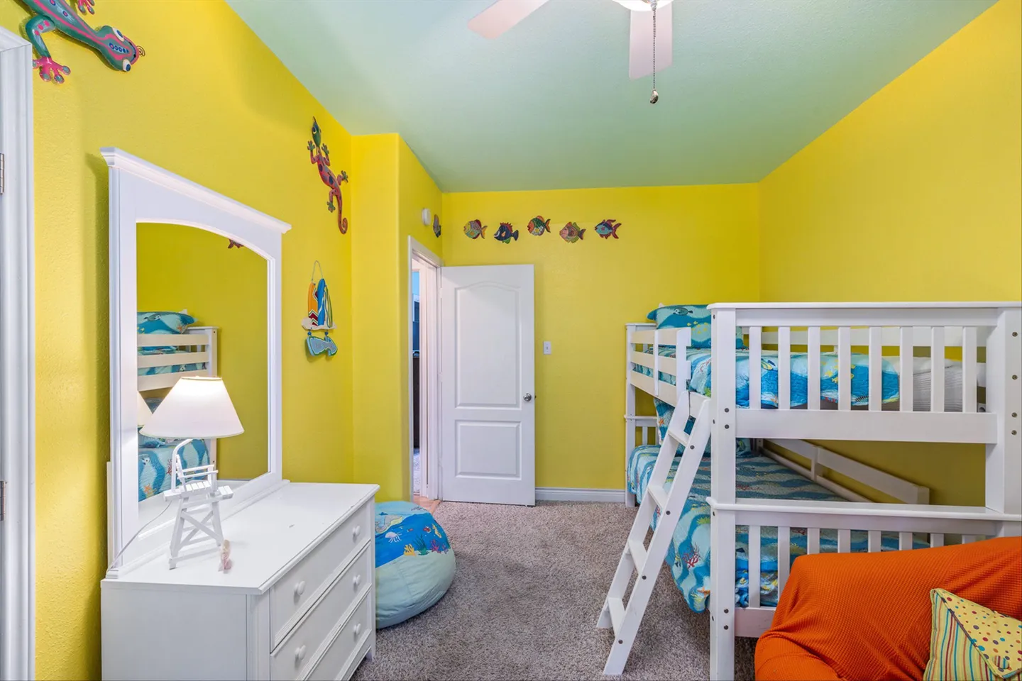 Bedroom with bright yellow walls, light blue ceiling, white bunk beds, and a white dresser with an attached mirror.