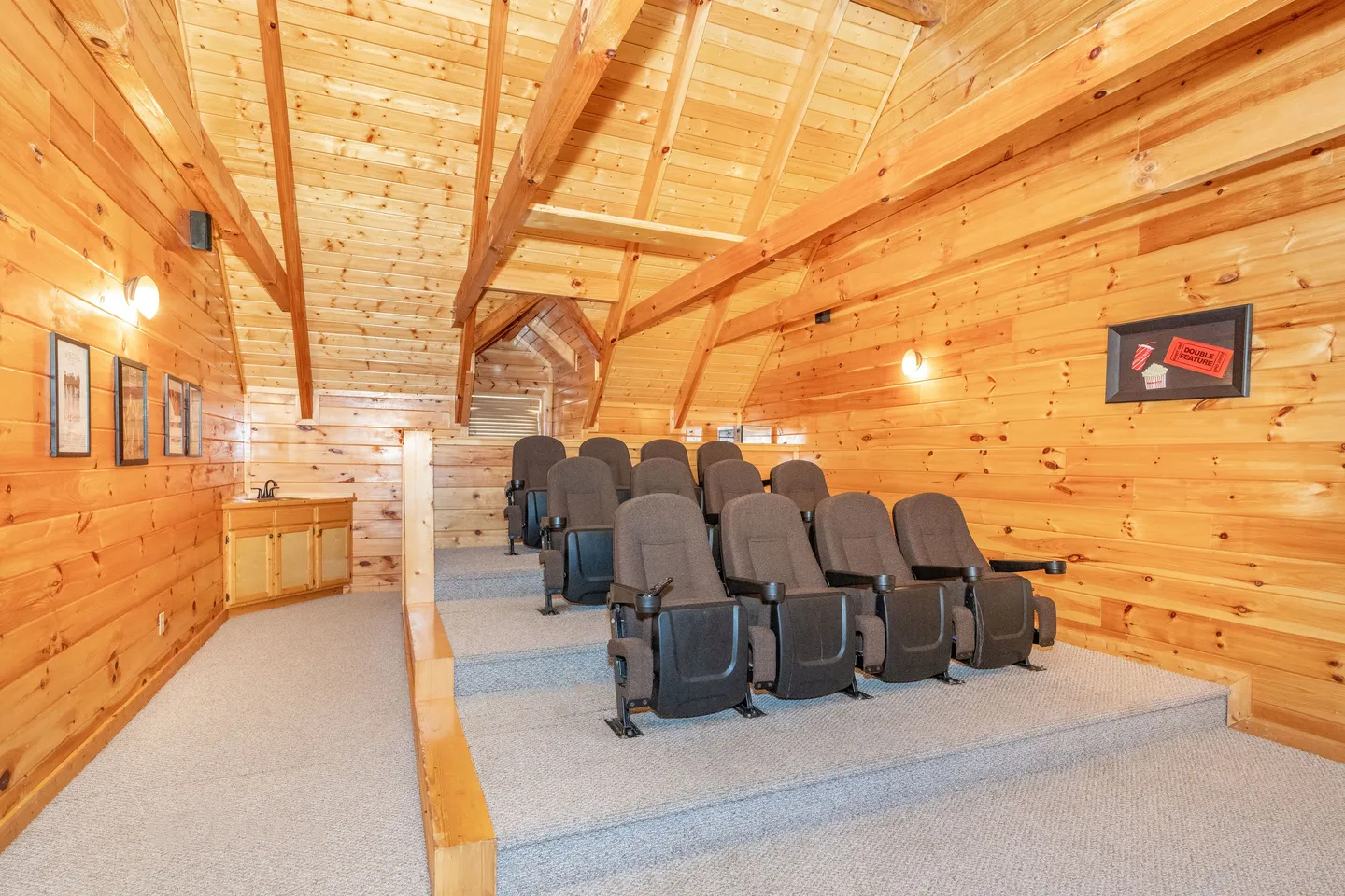 A home theater room with tiered rows of movie theater seats under wood-paneled cathedral ceilings.