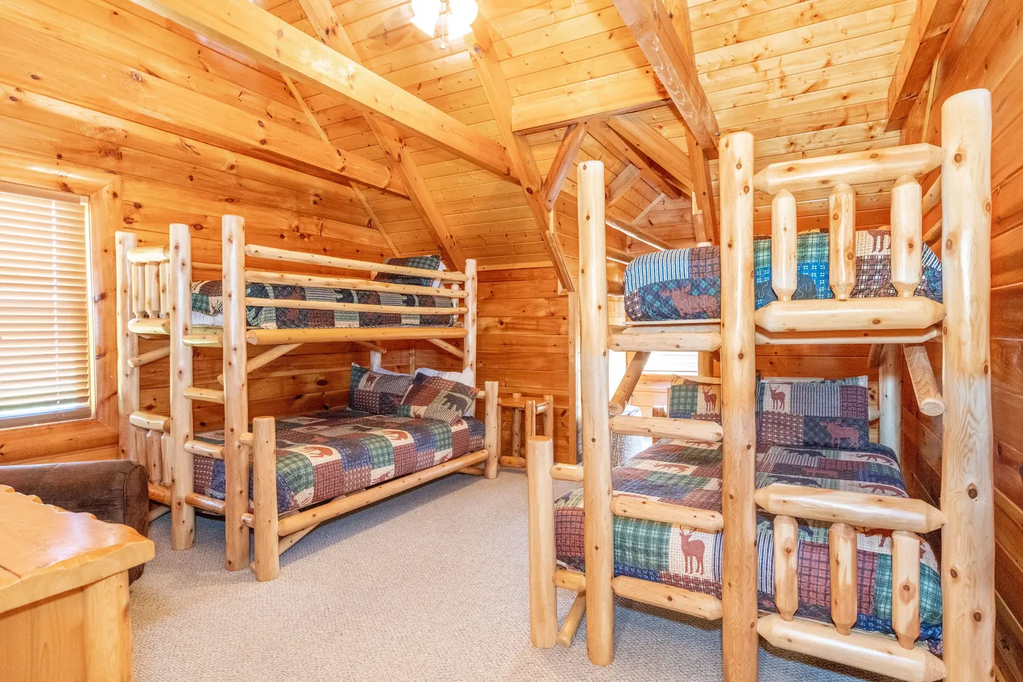 Bedroom with log-style bunk beds, wood-paneled walls, vaulted ceiling with exposed beams, and carpeted floor.