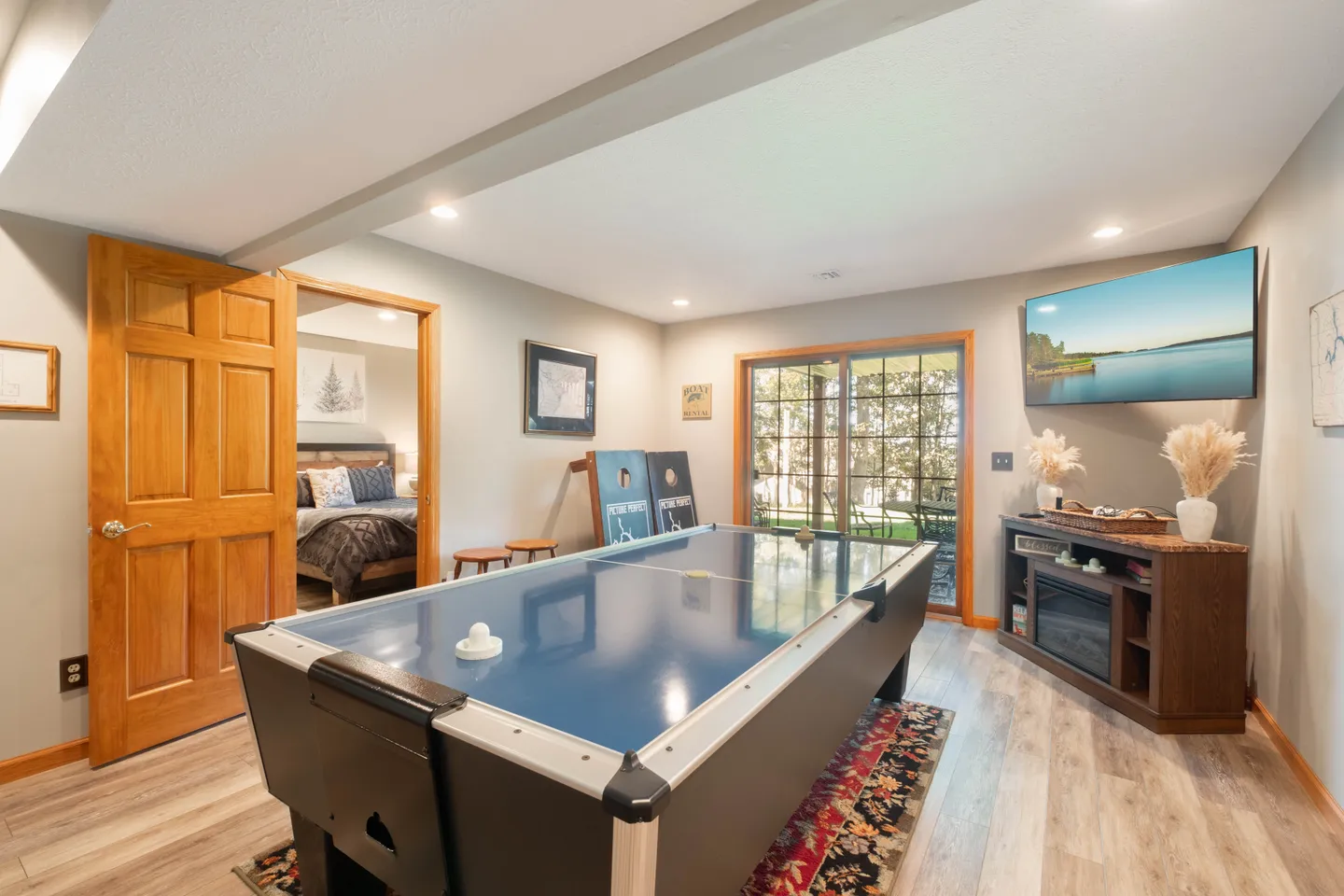 Game room featuring an air hockey table, a wall-mounted TV over an electric fireplace console, and sliding glass patio doors.