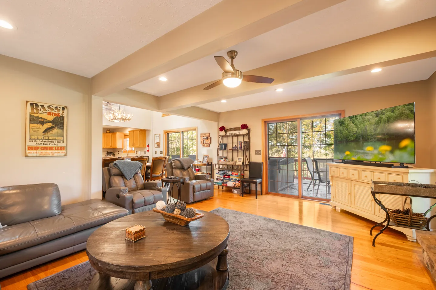 Living room with leather recliners, a round wooden coffee table, a television on a console, and sliding glass doors to a deck.