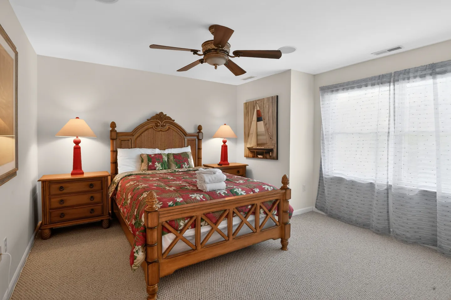 Bedroom featuring a wooden carved bed frame, matching nightstands with red lamps, and carpeted flooring.