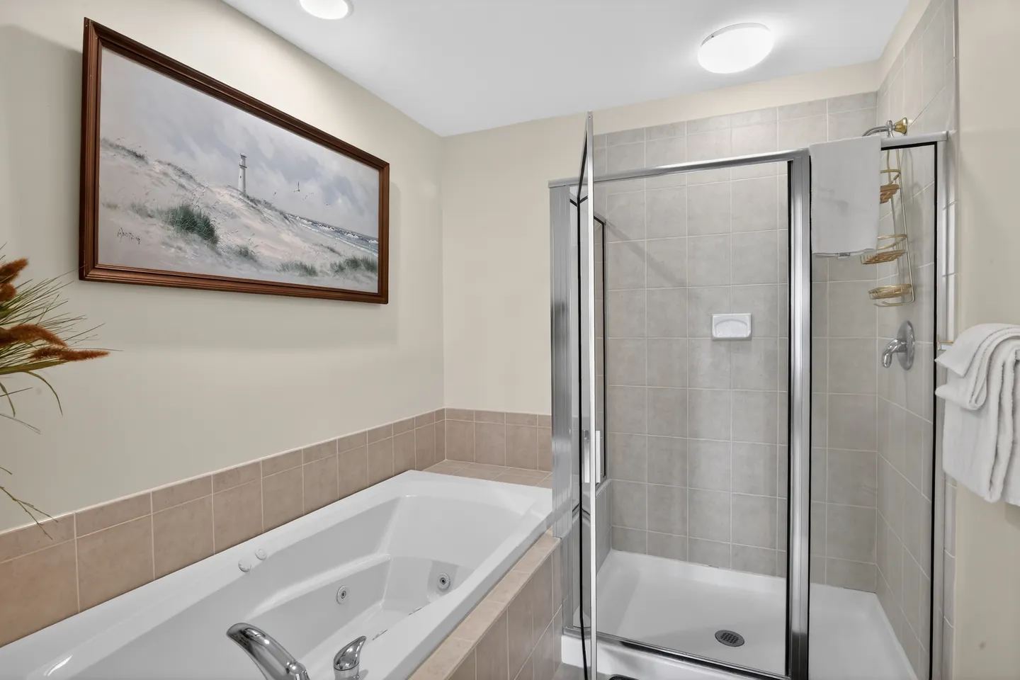 Bathroom with a drop-in jetted tub next to a glass-enclosed walk-in shower with tile walls.