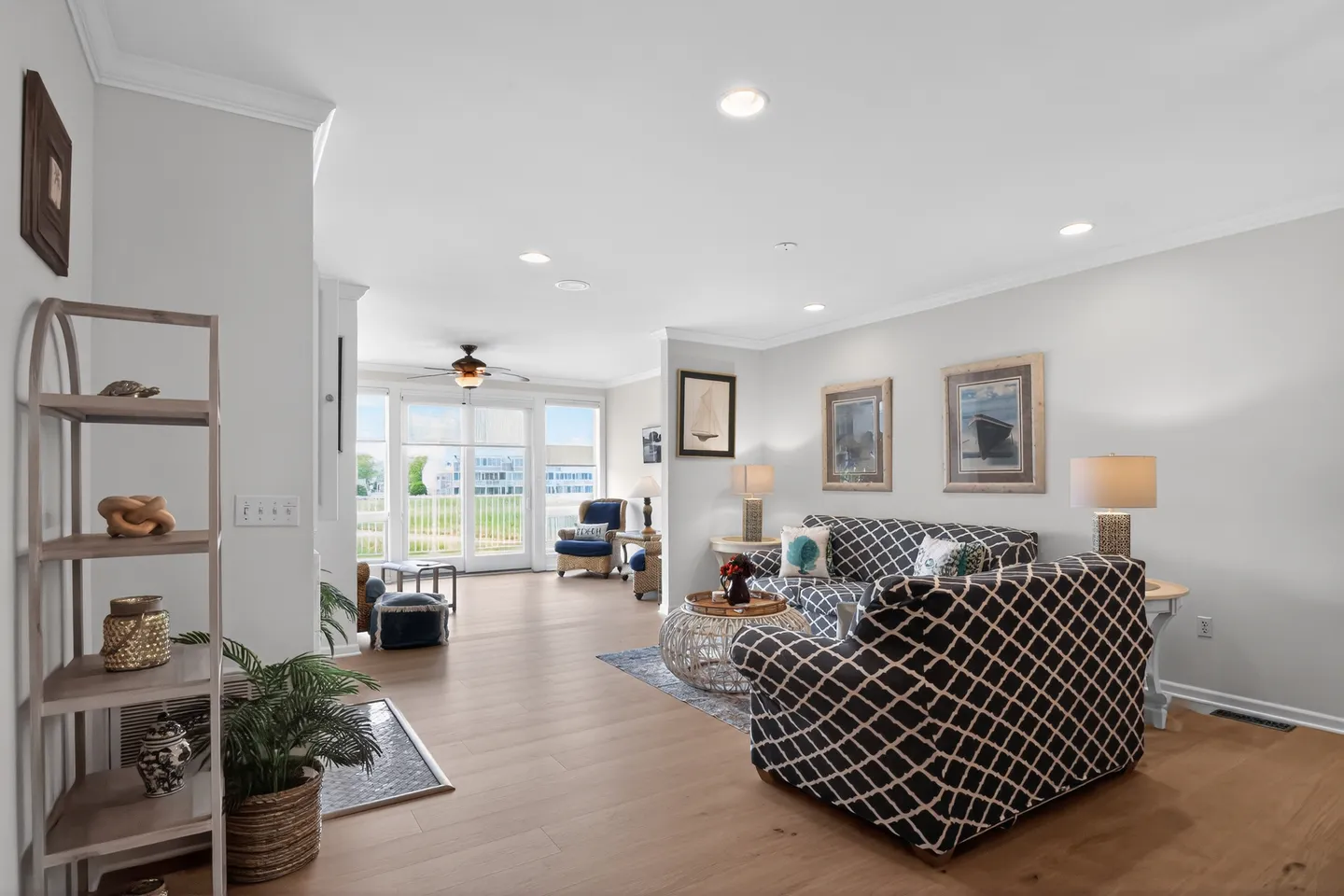 Open-concept living room with geometric patterned sofas, wood-style flooring, and large windows leading outdoors.